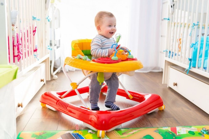 Un bambino dentro il suo girello che gioca
L'importanza del girello: pro e contro