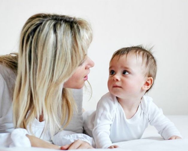 Una mamma che parla al suo neonato.
Mamma e neonato sono sdraiati e il piccolo la guarda interessato La prima parola dei nostri bambini? Mamma o papà?