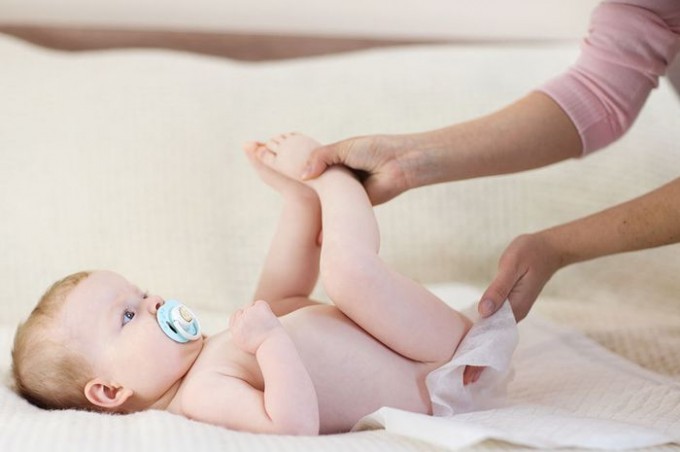 Mamma che cambia il pannolino al suo neonato mentre è sdraiato sul fasciatoio Pannolini tossici: tutte le marche e i modelli incriminati