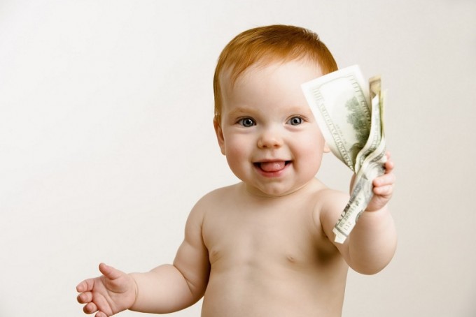 Quanto costa crescere un figlio oggi?
Neonato con delle banconote nella mano. Quanto costa crescere un bambino nel primo anno di vita?