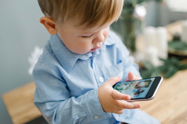 Un bambino con la camicetta celeste che gioca con uno smartphone.
Un bambino che gioca con uno smartphone